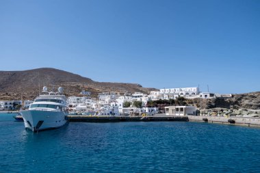 Folegandros Yunan limanına demirlemiş. Karavostasi rıhtımında demirli motorlu tekne, beyaz binalar ve mavi gökyüzü arka planı. Yunanistan 'ın Kiklad kentinde yaz tatili