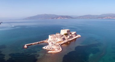 Yunanistan, Bourtzi, Nafplio limanının girişindeki Venedik su kalesi. Hava aracı görüntüsü. Mavi gökyüzü, dalgalı deniz arka planı.