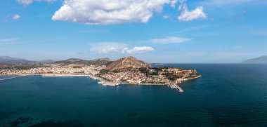 Nafplio ya da Nafplion şehri, Yunanistan, hava aracı panoramik görüntüsü. Moreloponnese eski şehir manzarası, Palamidi şatosu yokuş yukarı, rıhtıma demirlemiş yatlar ve tekneler. Bulutlu mavi gökyüzü.