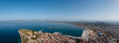 Yunanistan, Nafplio şehri ve limanı, insansız hava aracı panoramik manzarası. Mora 'nın eski şehir manzarası ve limanın girişindeki BourtziVenetian su kalesi. Mavi gökyüzü, dalgalı deniz arka planı.