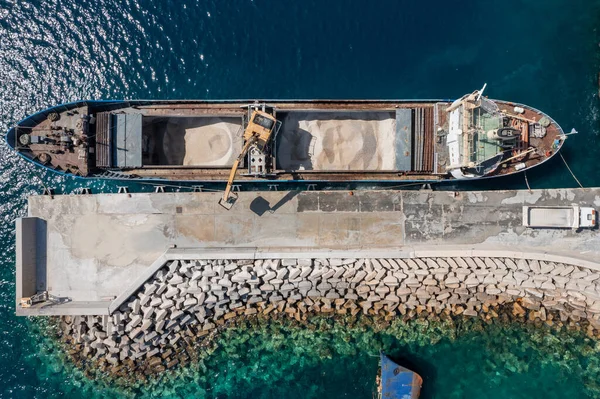 Marine works construction equipment and machinery, aerial drone top down view, Sand loading machine on a ship at Korissia port, Kea Tzia island, Cyclades, Greece