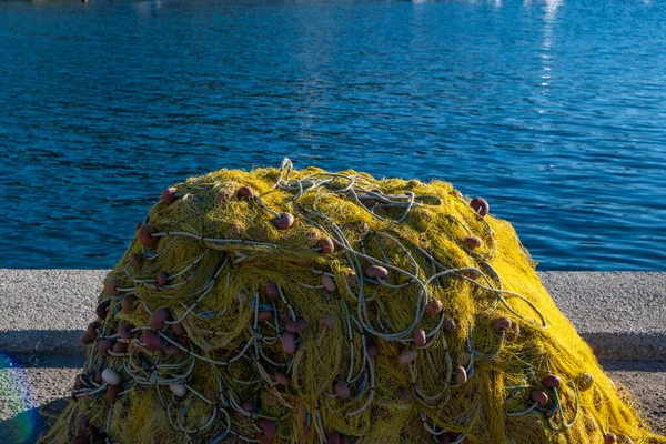 渔网堆积在渔民港口码头上晒干了 黄色的鱼网 有绳子和浮动在波纹的海底背景上 希腊Cyclades岛渔民设备 — 图库照片