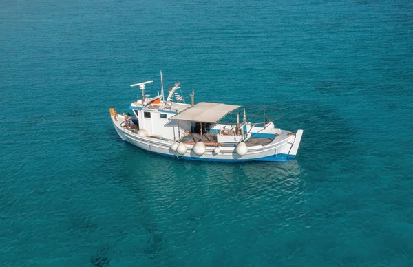 蓝绿色海底色的渔船 空中无人驾驶飞机视图 蓝色和白色的传统拖网渔船停泊在爱琴海 阳光灿烂的一天 希腊岛屿暑假 目的地希腊 — 图库照片