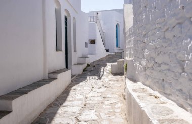 Sifnos Adası, Kiklad Yunanistan. Geleneksel Yunan beyazlatılmış taş duvar binaları güneşli arka planda dar kaldırım taşları boş. Varış yeri yaz tatili seyahati rahatla bir köy keşfet