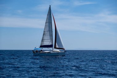 Ege Denizi Yunanistan 'da yelken açmak. Açık beyaz yelkenli yelkenli sakin dalgalı deniz, mavi gökyüzü arka planı, güneşli bir gün. Cyclades adalarında yaz tatilleri.