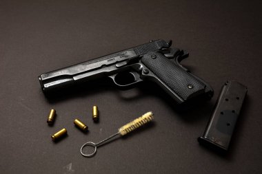 9mm 'lik silah, şarjör, mermi kovanları ve siyah arka planda temizlik çubuğu. Kara metal silah bakımı, askeri ve güvenlik konsepti için otomatik tabanca. Yan görünüm