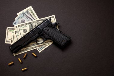 Suç parası, mafya ve yolsuzluk kavramı, suç kavramı, tabanca tabancası 9 mm ve siyah arkaplan üzerine Amerikan doları banknotları.