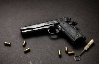 9mm 'lik tabanca, şarjör, mermi kovanları ve siyah arka planda temizlik çubuğu. Kara metal silah bakımı, askeri ve güvenlik konsepti için otomatik tabanca. Yan görünüm