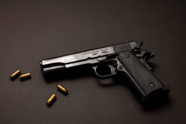 9mm 'lik tabanca ve siyah arka planda mermi. Siyah metal silah, ordu için otomatik tabanca ve klasik bir masada güvenlik. Yan görünüm