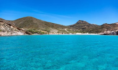 Milos Adası, Plathiena boş kumlu plaj, Cyclades Yunanistan. Meşhur şeffaf şeffaf turkuaz Ege denizi tepedeki berrak mavi gökyüzü binaları. Yaz tatili tatil günü güneşli. 