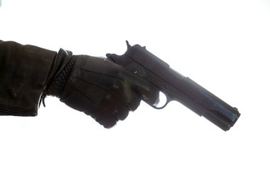 Katil beyaz arka planda izole edilmiş bir tabancayla silahlanmış, eldiven eldiveni yakın çekim görüntüsü tutuyor. Silahlı adam, katil ve mafya yargılama kavramı