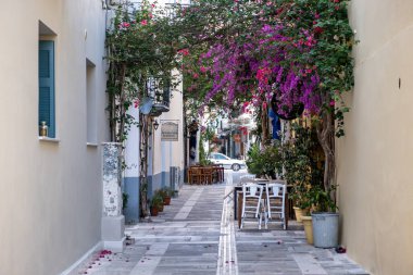 Nafplio, Mora, Argolida, Yunanistan. 28 Haziran 2021. Ahşap sandalyeli kafe tavernası restoranı kırmızı süslemeli bougainvilleas boş kaldırım taşı. Tatil yeri Nafplion şehri.