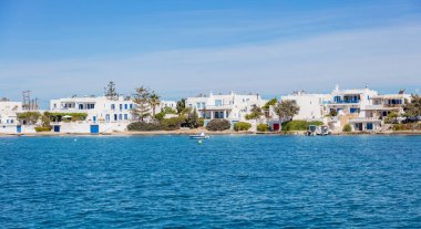 Milos Adası Yunanistan 'da. Beyazlatılmış binalar Cyclades geleneksel mimarisi Pollonia köyünde beyaz ve mavi renklerle. Sakin mavi denize demirlemiş kumsaldaki balıkçı tekneleri.