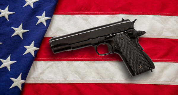 Pistol on US America flag background, top view. Gun laws in United states, self defence and security concept