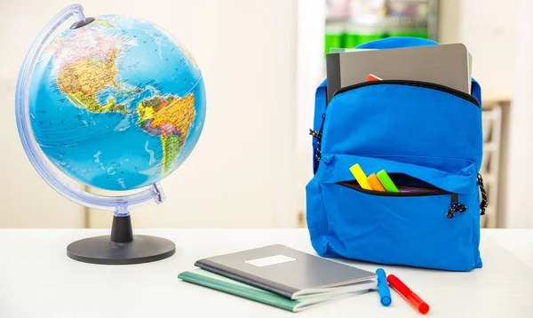 Back to school. Student backpack and supplies on white desk, blur interior room background. Education, study concept