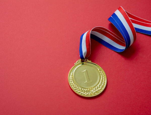 Medal gold, Winner prize award and red blue color ribbon. Athlete trophy in sport for first place champion isolated on red background, copy space, template.