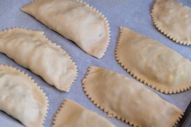 Kalitsounia pişirmek için çubuksuz kağıtta pişmemiş turtalar. Kaltsounia 'nın üstünde Girit Adası' nın geleneksel gıdaları otlar ve susam tohumları içeren hamur hamuru. Ballı yumurtalar.