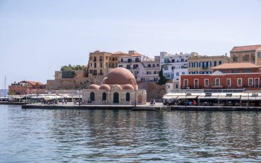 Hanya, Yunanistan, 23 Mayıs 2025. Eski Venedik limanındaki tarihi Hasan Paska Camii, rıhtım kafeleri, taş duvarlar ve Girit adasındaki renkli binalar.