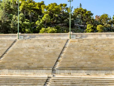 Yunanistan 'ın Atina kentindeki Panathenaic Stadyumu' nda yeşil ağaçların altında boş mermer koltuklar