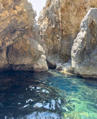 Doğal kayalık deniz mağarası girişi, engebeli sahil uçurumu boyunca berrak turkuaz su, güneşli bir gün. Korfu Adası Yunanistan