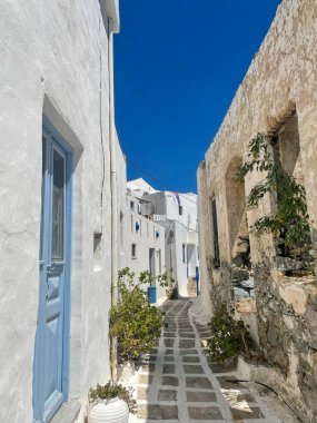 Yunanistan, Serifos Adası, Kiklad geleneksel mimarisi. Taş döşeli bir sokakta beyaz duvarlı evler, ahşap kapılar ve pencereler ve saksı bitkileri, mavi yaz gökyüzü..