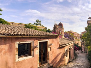 Korfu adası eski kasaba mimarisi. Tenedos Manastırı, kaldırım taşlı bir sokakta. Kilise çanı kulesi, mavi gökyüzü, Yunanistan.