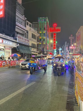 Bangkok, Tayland, 7 Kasım 2025. Tuk tuk ve arabaların gece trafiği, Çin Mahallesi 'ndeki Yaowarat Yolu' ndaki sokak yemekleri, parlak neon tabelalar.