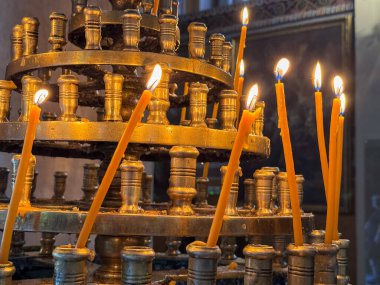 Yunanistan 'ın Atina kentindeki bir ortodoks Hıristiyan kilisesinde, pirinçten mumların üzerinde dua mumları yakar. Parlayan ılık alçak ışık