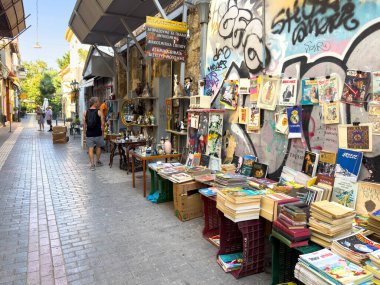 Atina, Yunanistan, 9 Ağustos 2025. Monastiraki bit pazarı, dar bir yaya sokağı boyunca kitap ve antikalar, duvarda grafiti.
