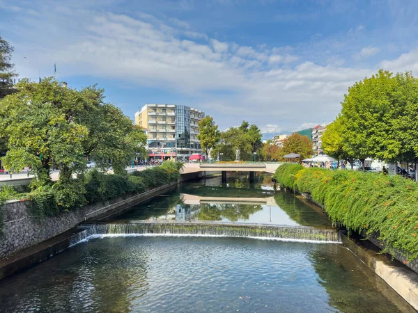Trikala, Yunanistan, 26 Ağustos 2025. Şehir merkezinde alçak Weir ve Köprüsü olan şehir nehir kanalı, yeşil ağaçlar ve binalar, güneşli yaz günü