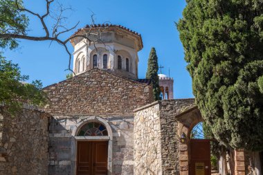 Yunanistan 'ın Chios Adası' ndaki Nea Moni manastırı avlusunda. Sessiz bahçede selvi ağaçları ve taş duvarlar, berrak mavi gökyüzü..