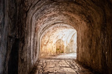 Eski Yunan Korfu Adası 'ndaki Eski Kale' nin içindeki taş tünel geçidi. Parke taşları üzerinde parlak bir çıkış, yumuşak gün ışığında.
