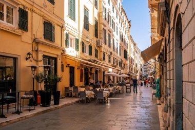 Korfu, Yunanistan, 4 Haziran 2025. Pastel binaları, eski şehrin tarihi merkezinde açık hava kafeleri olan canlı bir yaya caddesi..