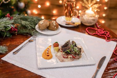 Biber şeritli ızgara sığır eti madalyonları, tatlı püre, kiraz domatesleri ve mikroyeşiller, arkada parlayan ışıklar..