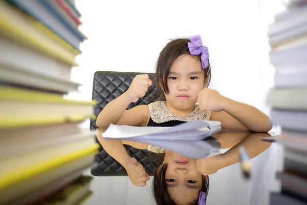 Little school girl wearing an overall doing homework