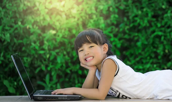 Glückliches kleines Mädchen, das Spaß beim Laptop spielen hat — Stockfoto