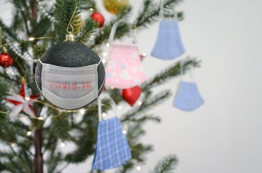 Sosyal issuse virüsü koronasıyla ya da covid 19 konseptiyle kutlama. Koruyucu maskeli Noel ağacı süsü.