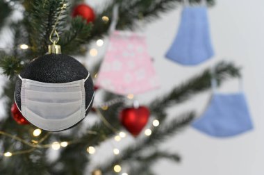 Sosyal issuse virüsü koronasıyla ya da covid 19 konseptiyle kutlama. Koruyucu maskeli Noel ağacı süsü.