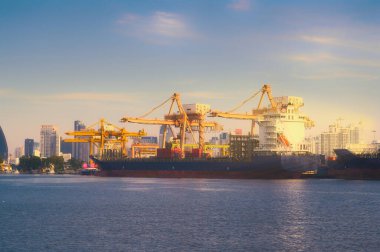 Tersane arka planında çalışan vinç köprüsüne sahip Uluslararası Konteyner Kargo gemisi, lojistik ithalat arka planı ve taşımacılık endüstrisi. 