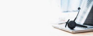 Kulaklık, ofis masasında iletişim, destek, çağrı merkezi ve müşteri hizmetleri yardım masası konsepti. Kopyalama alanı olan pankart arkaplanı