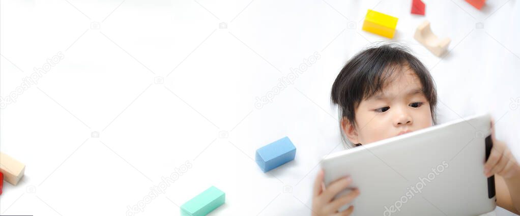 a little girl down playing mobile games on the tablet. Learning, education and communication on the Internet using. banner background with copy space