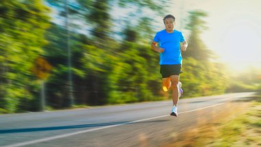Male runner sprinting on empty road with motion blur. Outdoor fitness, speed training, endurance exercise and healthy lifestyle concept.