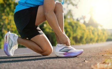 Koşmadan önce ayakkabı bağcıklarını yolda bağlayan koşucuyu kapat. Açık hava fitness, spor hazırlık, sağlıklı yaşam tarzı ve eğitim konsepti.