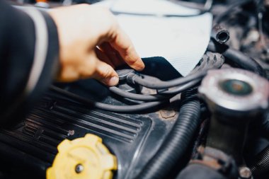 Tamirci arabanın bujilerindeki yüksek voltajlı kabloları kontrol ediyor..