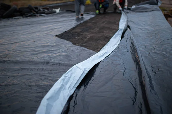 Roof waterproofing. Building construction. A waterproof film is applied to the roof of the house. Installation of a waterproofing layer. Construction works.