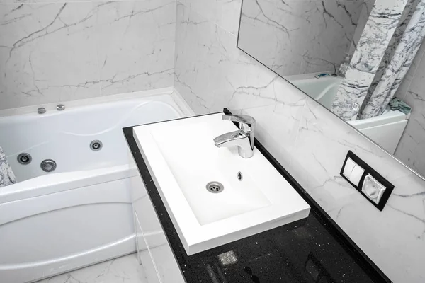 modern bathroom interior, marble tiles, mirror, jacuzzi, white vanity unit.