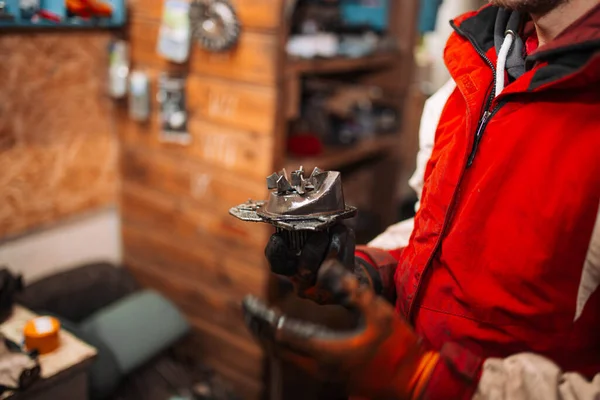 Arabanın su pompasının değiştirilmesi, araba tamircilerinin elinde iki pompa, eski hasarlı ve yeni.