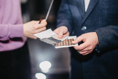 Müşteri-alıcı ve stilist-moda tasarımcısı terzilik için kumaş örneklerini inceler.