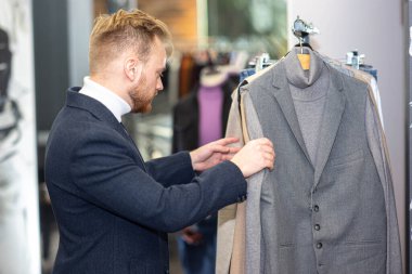  Dükkanda kıyafet seçen iş elbiseli bir adam. Adam alışveriş yapıyor..