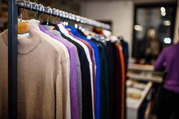 classic sweaters  on a hangers in a clothing store. natural material, wool, linen cotton.